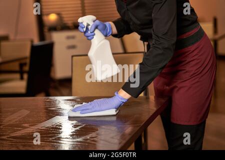 Operaio del ristorante che lava un tavolo spruzzato con un panno Foto Stock