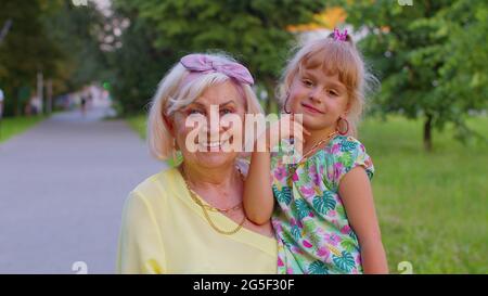 Bambina piccola nipote abbracciando baciare con la nonna nel parco, felice rapporto di famiglia Foto Stock