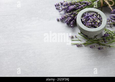 Ciotola fresca di fiori di lavanda su fondo grigio di cemento, spazio copia Foto Stock