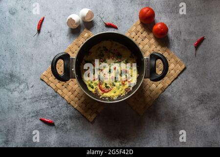 La frittata è un piatto italiano a base di uova o omelette a base di uova strapazzate, verdure al formaggio, cipolla, pomodoro e pepe. Vista dall'alto. Foto Stock