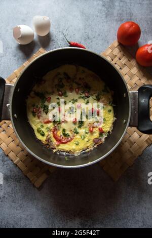Frittata tradizionale piatto italiano a base di uova preparato a fuoco lento con ingredienti di cipolla e peperoncino al pomodoro. Vista dall'alto. Foto Stock