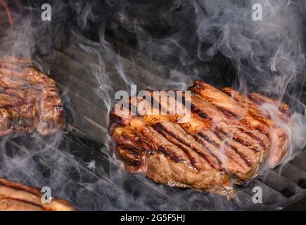 Primo piano con bistecche di manzo al ribeye al fuoco aperto con griglia in metallo ghisa, vista ad alta angolazione Foto Stock