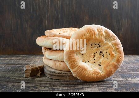 Una pila di flapjack tondo non lievitato su sfondo di legno. Semplice pane rustico al sesamo. Foto Stock