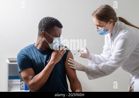 Vaccinazione durante la pandemia di covid, giovane infermiera che fa l'iniezione. Foto Stock