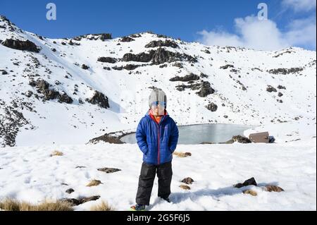 Ragazzo intelligente nella neve con giacca e refrigeratori Foto Stock