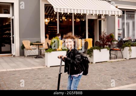 L'elegante bambina guida uno scooter in città Foto Stock