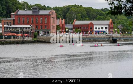 WESTPORT, CT, USA - 26 GIUGNO 2021: Edifici in mattoni rossi vicino al fiume Saugatuck con ponte e barca a remi Foto Stock