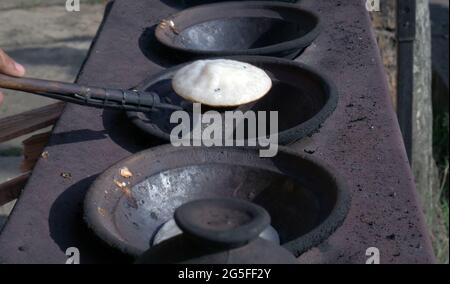 Primo piano di serabi o frittelle cucinate a mano della madre in una padella fatta di terreno. Foto Stock