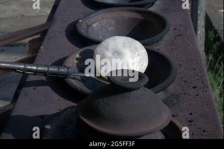 Primo piano di serabi o frittelle cucinate a mano della madre in una padella fatta di terreno. Foto Stock