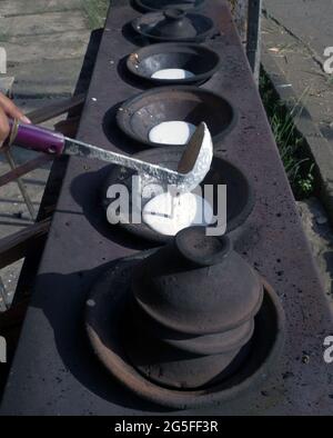 Primo piano di serabi o frittelle cucinate a mano della madre in una padella fatta di terreno. Foto Stock