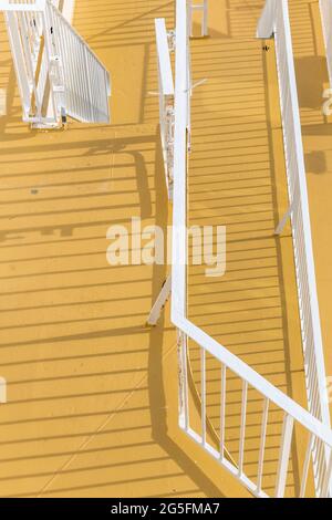 Ombre di ringhiere e scale su un pavimento giallo Foto Stock