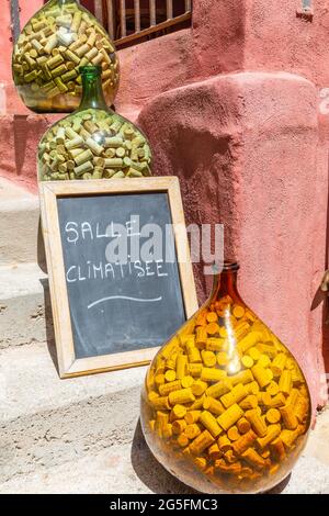 Tre demijohn pieni di tappi, posti sui gradini di un ristorante. Calvi, Corsica, Francia Foto Stock