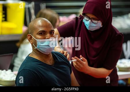 Watford, Regno Unito. 27 giugno 2021. Un uomo riceve una prima dose del vaccino Pfizer in una clinica pop-up di vaccinazione di massa presso il Vicarage Road Stadium del Watford FC come parte della campagna "Grab a jab". Il NHS sta inoltre promuovendo un certo numero di ambulatori di walk-in questo fine settimana attraverso la capitale per cercare di aumentare il numero di oltre 18 che ricevono un jab come casi della variante di Delta sono riportati per essere in aumento. Credit: Stephen Chung / Alamy Live News Foto Stock