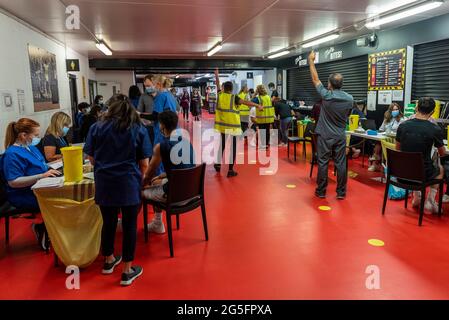 Watford, Regno Unito. 27 giugno 2021. Persone che ricevono una prima dose del vaccino Pfizer in una clinica pop-up di vaccinazione di massa presso il Vicarage Road Stadium del Watford FC come parte della campagna "Grab a jab". Il NHS sta inoltre promuovendo un certo numero di ambulatori di walk-in questo fine settimana attraverso la capitale per cercare di aumentare il numero di oltre 18 che ricevono un jab come casi della variante di Delta sono riportati per essere in aumento. Credit: Stephen Chung / Alamy Live News Foto Stock