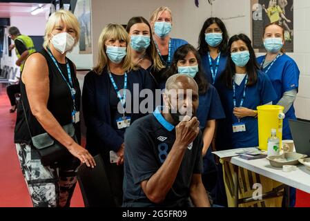 Watford, Regno Unito. 27 giugno 2021. L'ex giocatore di Watford Luther Blissett si pone con il personale medico presso una clinica pop-up di vaccinazione di massa al Vicarage Road Stadium del Watford FC come parte della campagna "Grab a jab". Il NHS sta inoltre promuovendo un certo numero di ambulatori di walk-in questo fine settimana attraverso la capitale per cercare di aumentare il numero di oltre 18 che ricevono un jab come casi della variante di Delta sono riportati per essere in aumento. Credit: Stephen Chung / Alamy Live News Foto Stock