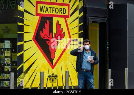 Watford, Regno Unito. 27 giugno 2021. Un uomo che indossa un maschera al di fuori di una clinica pop-up di vaccinazione di massa al Vicarage Road Stadium del Watford FC come parte della campagna "Grab a jab". Il NHS sta inoltre promuovendo un certo numero di ambulatori di walk-in questo fine settimana attraverso la capitale per cercare di aumentare il numero di oltre 18 che ricevono un jab come casi della variante di Delta sono riportati per essere in aumento. Credit: Stephen Chung / Alamy Live News Foto Stock