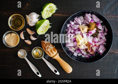 Preparazione degli ingredienti per la marinata alla bistecca: Cipolla tagliata a dadini, aglio sminuzzato e altri ingredienti di marinata su un recipiente piccolo Foto Stock