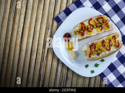 Hot dog con verdure, senape gialla, ketchup, su fondo di legno. - immagine ad alta risoluzione Foto Stock