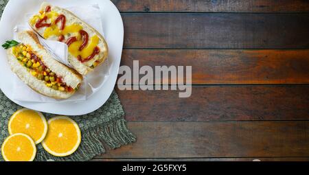 Hot dog con verdure, senape gialla, ketchup, su fondo di legno. - immagine ad alta risoluzione Foto Stock