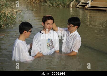 Pastore protestante coreano e un altro uomo battezzano un adolescente, tutti indossano abiti bianchi, a Qasr El Yahud, fiume Giordano, qui Gesù Cristo è stato battezzato, Foto Stock