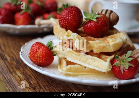 Waffle belgi con fragole fresche, miele e cappuccino a colazione Foto Stock