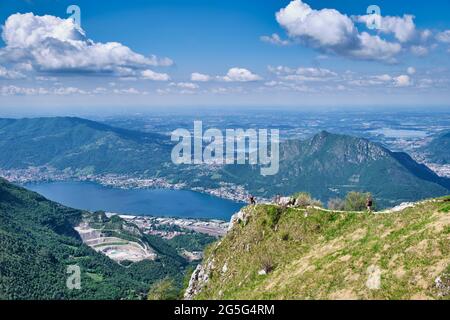 Uomini che camminano sulla cima della montagna con un bel panorama sullo sfondo del Lago di Como - piani d'Erna, Lombardia, Italia Foto Stock