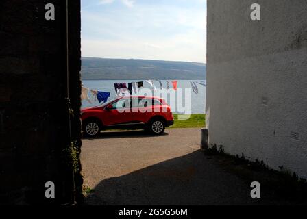 Scena domestica a Inveraray, Argyll & Bute, Scozia con auto parcheggiata dietro edificio e lavaggio appeso sulla linea accanto a Loch Fyne Foto Stock