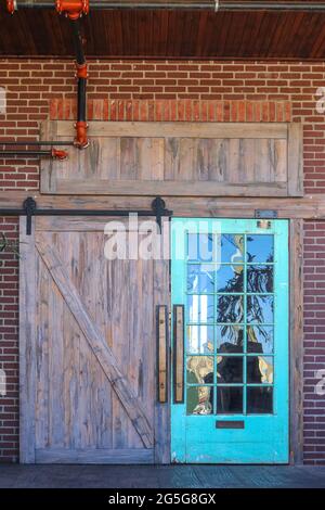 Unico rustico fienile porta d'ingresso all'edificio con riflesso della natura in un lato con lastre di vetro, tutti in mattoni con tubi idraulici rossi visibili Foto Stock