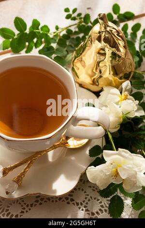 rose da tè in una tazza bianca su un tavolo di legno. stile rustico. Immagine verticale Foto Stock