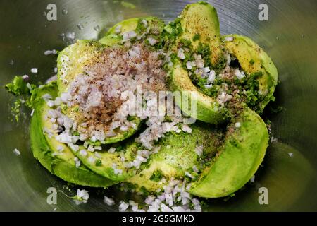 avocado sminuzzato con cipolle tritate ed erbe con sale e pepe condimento Foto Stock