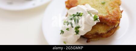 Frittelle di patate con panna acida adagiata su un piano di chiusura bianco Foto Stock