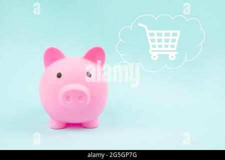 Pink piggy bank con ologramma digitale carrello di shopping in nuvola pensato sopra la sua testa su sfondo blu Foto Stock