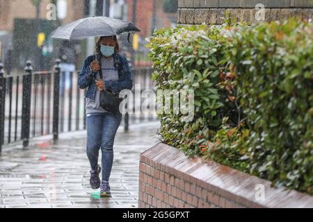 Londra, Regno Unito. 18 Giugno 2021. Una donna si ripara dalla pioggia sotto un ombrello durante le precipitazioni a Londra. Credit: Dinendra Haria/SOPA Images/ZUMA Wire/Alamy Live News Foto Stock