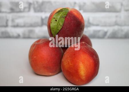 Una pila di 4 pesche con una foglia sulla pesca superiore Foto Stock