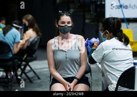 Toronto, Canada. 27 Giugno 2021. Una donna che indossa una maschera facciale riceve una dose del vaccino COVID-19 in un sito di vaccinazione di massa a Toronto, Canada, il 27 giugno 2021. La città di Toronto ha ospitato una vaccinazione di massa di un giorno la domenica come Toronto Vaccine Day per vaccinare circa 25,000 persone contro COVID-19 da 400 vaccinatori. Credit: Zou Zheng/Xinhua/Alamy Live News Foto Stock