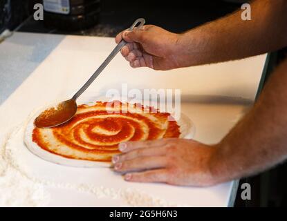 chef prepara la pizza con pomodoro fritto spalmato a spirale Foto Stock