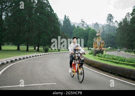 fratello prende sua sorella in divertente bicicletta a cavallo nel parco Foto Stock