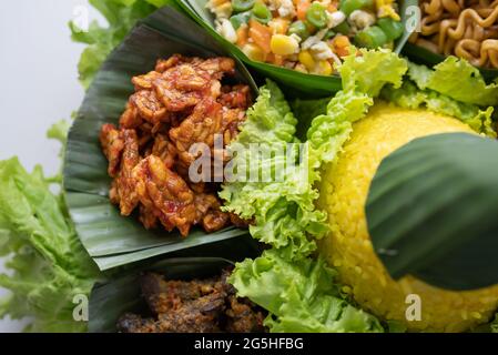 nasi tumpeng. cucina indonesiana riso giallo su foglia di banana Foto Stock