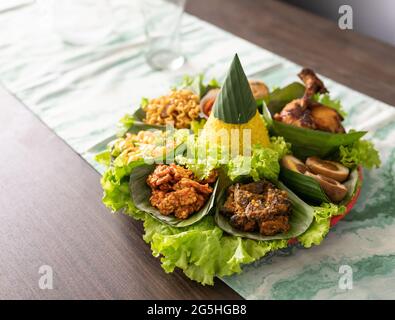 nasi tumpeng. cucina indonesiana riso giallo su foglia di banana Foto Stock