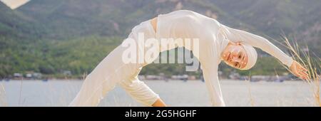 BANNER, LUNGA FORMATO Kundalini yoga donna in abiti bianchi e turbani pratica yoga kundalini sullo sfondo del mare, montagne e tramonto Foto Stock