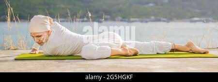 BANNER, LUNGA FORMATO Kundalini yoga donna in abiti bianchi e turbani pratica yoga kundalini sullo sfondo del mare, montagne e tramonto Foto Stock