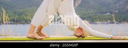 BANNER, LUNGA FORMATO Kundalini yoga donna in abiti bianchi e turbani pratica yoga kundalini sullo sfondo del mare, montagne e tramonto Foto Stock