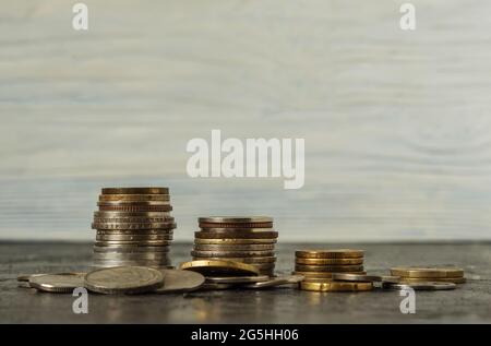 Su uno sfondo nero, ci sono quattro pile di monete in ordine decrescente. Le monete sono sparse in primo piano. Pianificazione aziendale, finanza e. Foto Stock