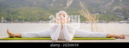 BANNER, LUNGA FORMATO Kundalini yoga donna in abiti bianchi e turbani pratica yoga kundalini sullo sfondo del mare, montagne e tramonto Foto Stock