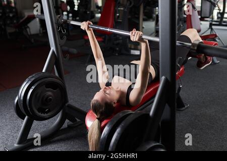 Fiducioso più taglia giovane caucasica facendo pressa inclinata del panca del barbell nella palestra Foto Stock