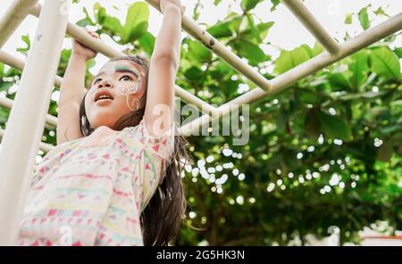 ragazza sana appesa su un bar nel parco giochi Foto Stock