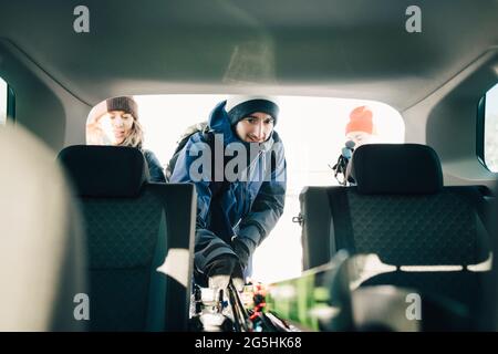 Uomo che carica sci nel bagagliaio durante le vacanze Foto Stock