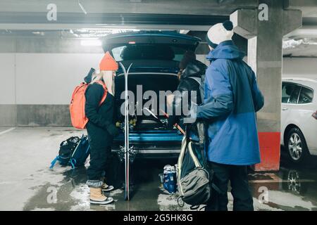 Amici di sesso maschile e femminile che caricano i bagagli nel bagagliaio dell'auto presso il garage Foto Stock