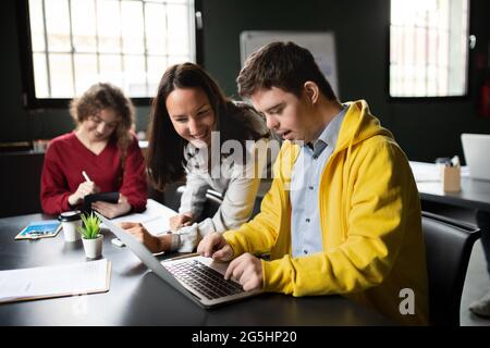 L'uomo della sindrome di Down frequenta la classe di istruzione nel centro della comunità, inclusività della persona disabile. Foto Stock