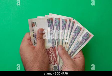 Valuta nazionale egiziana. Banconote in denaro. Le mani dell'uomo tengono le banconote in sterlina egiziana su sfondo verde Foto Stock